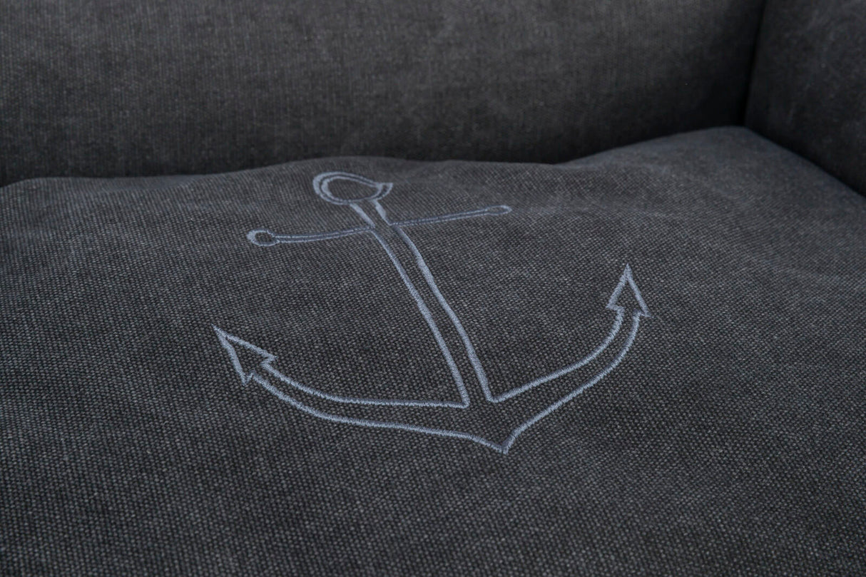 Graue Stoffoberfläche mit einem eingestickten, blauen Ankerdesign auf der Sitzfläche.