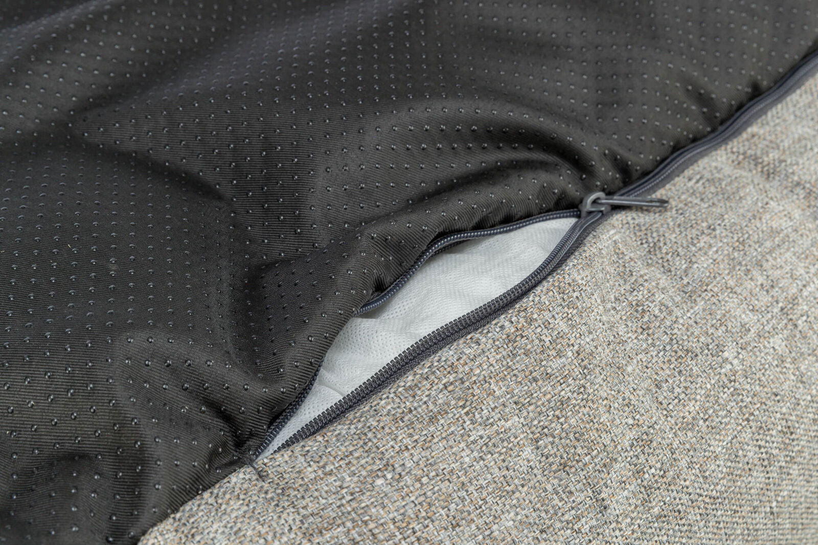 Nahaufnahme eines strukturierten Stoffes mit einem Reißverschluss, teilweise geöffnet, und schwarzem gefüttertem Innenmaterial.