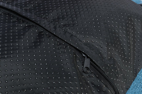 Schwarzer, punktiert gemusterter Stoff mit einem geschlossenen Reißverschluss in der Mitte auf blauem Hintergrund.