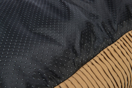 Dunkler, gepunkteter Stoff mit daneben liegendem geripptem, hellbraunem Stoff.