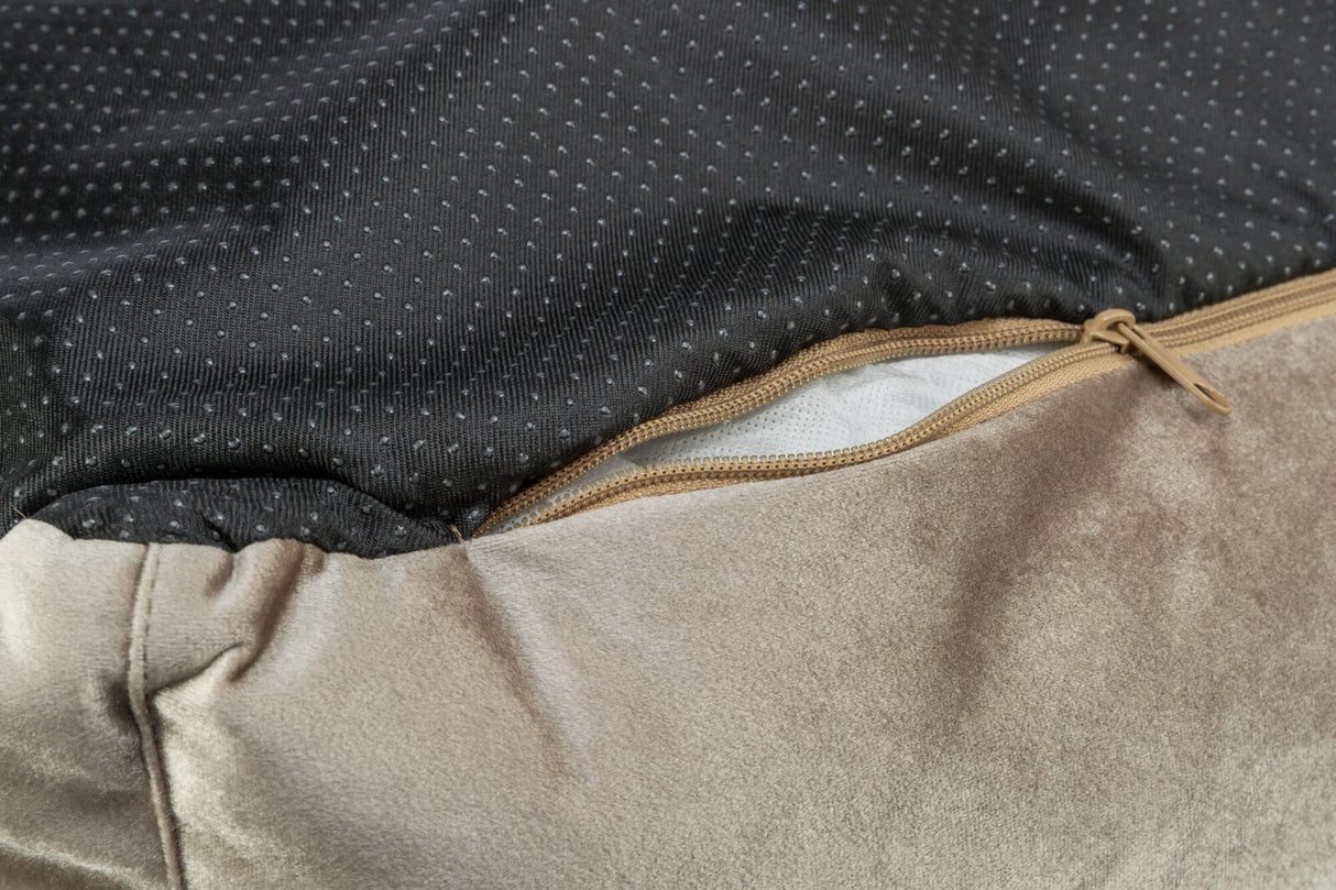 Nahaufnahme eines beige- und schwarzen Stoffes mit Reißverschluss, sichtbare weiße Polsterung darunter.