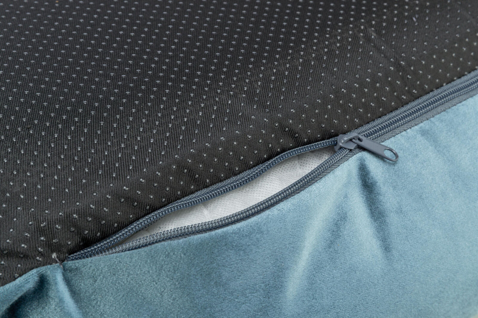 Reißverschluss auf blauem Stoff, der schwarzen Stoff mit kleinen Punkten verbindet.