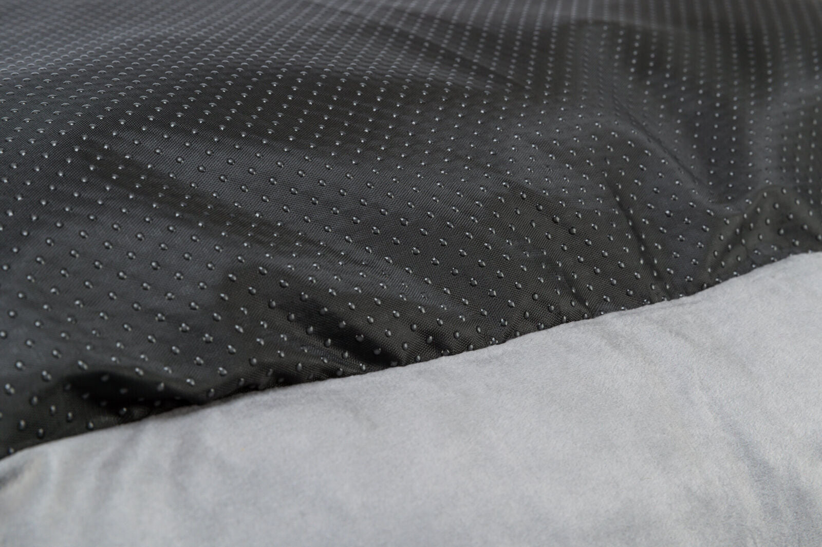Grauer Stoff im Vordergrund mit schwarzem, gepunktetem Stoff im Hintergrund.