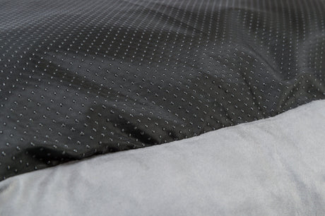 Grauer Stoff im Vordergrund mit schwarzem, gepunktetem Stoff im Hintergrund.