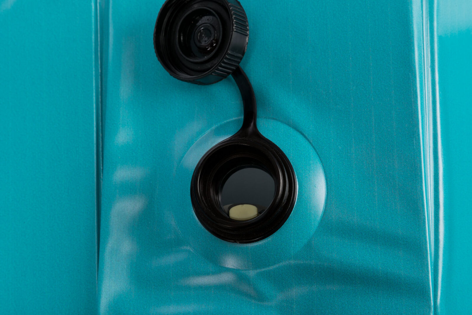 Schwarzer Schraubverschluss auf türkisfarbenem Hintergrund, Öffnung sichtbar.