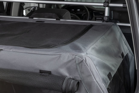 Transportbox mit grauem Stoff und schwarzen Netzeinsätzen befindet sich im Kofferraum eines Autos.