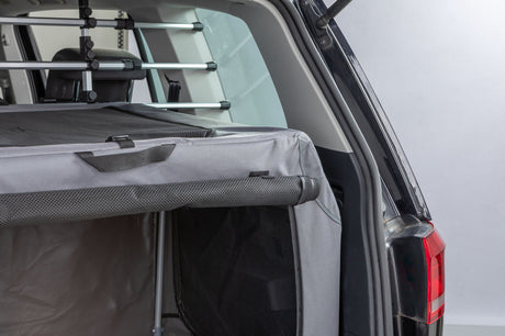 Graue Transportbox im geöffneten Kofferraum eines Autos.