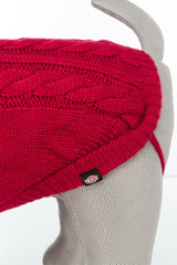 Roter Strickhundepullover mit Zopfmuster auf grauer Hundepuppe, Etikett mit Aufschrift "TRIXIE".