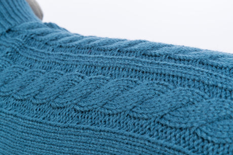Nahaufnahme eines blauen, gestrickten Stoffes mit Zopfmuster und feiner Textur.
