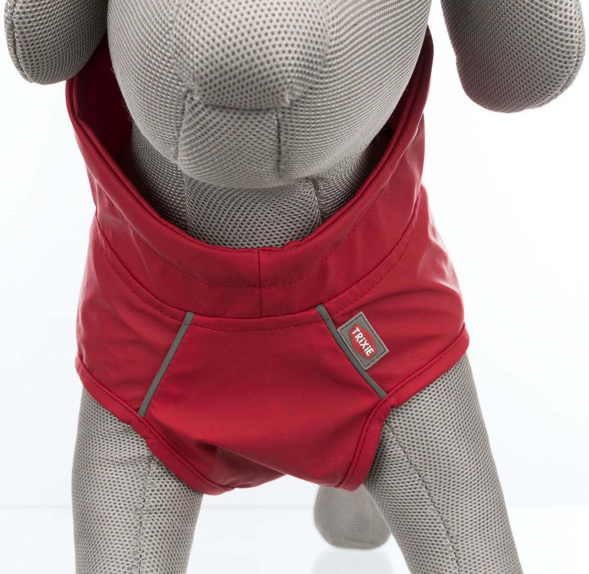 Ein roter Hundemantel auf einem grauen Hundemodell mit sichtbarem Markenschild "Trixie".