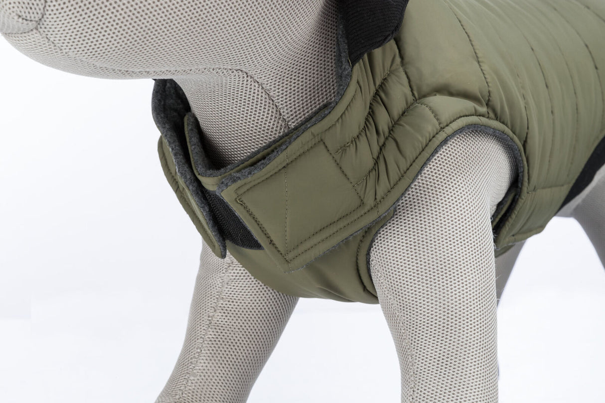 Graues Stoffmodell eines Hundes trägt eine olivgrüne gesteppte Hundejacke mit Klettverschluss.