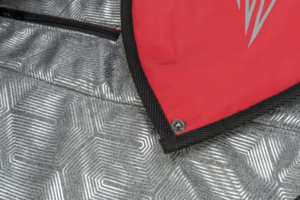 Rotes und silbernes Material mit geometrischem Muster, schwarze Kante und Druckknopf sichtbar.