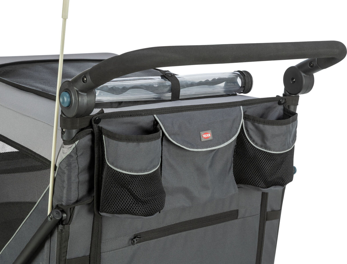 Ein grauer Transportwagen mit schwarzem Griff und mehreren Taschen, teilweise aus Netzmaterial, ist abgebildet.