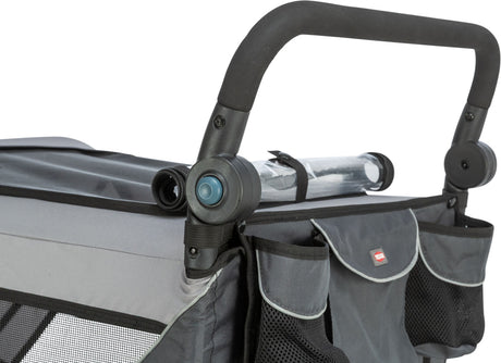 Schwarzer Griff eines grauen Fahrradanhängers mit Taschen und Netzfächern, Kunststoffrad und grauem Bezug.