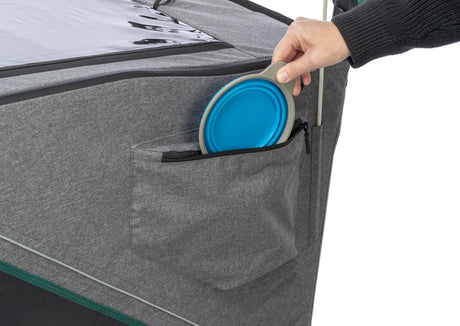 Graue Tasche mit Reißverschluss, eine Hand verstaut einen blauen faltbaren Gegenstand darin.