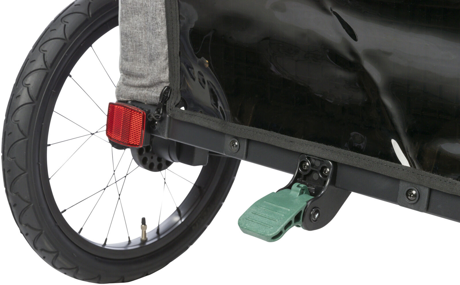 Rad eines Fahrradanhängers mit rotem Reflektor, schwarzem Schutzblech und grünem Pedal auf grauer Stoffbespannung.