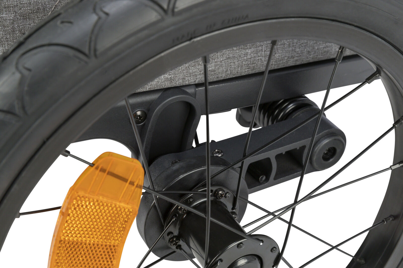 Nahaufnahme eines schwarzen Fahrradrades mit orangefarbenem Reflektor, Speichen und grauem Hintergrund.