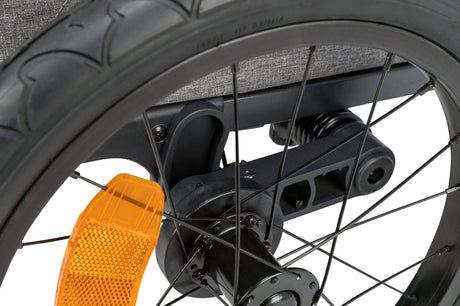 Nahaufnahme eines schwarzen Fahrradrades mit orangefarbenem Reflektor, Speichen und grauem Hintergrund.