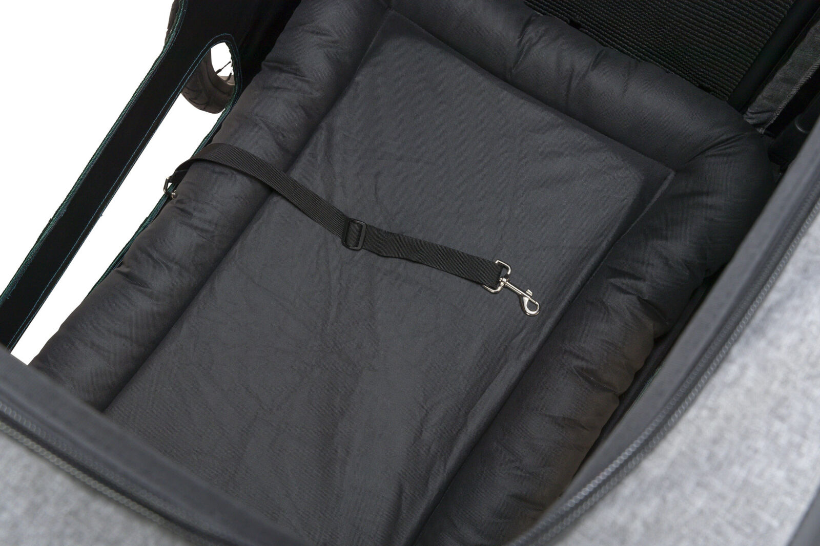 Innenansicht eines Fahrradanhängers mit schwarzer Polsterung und einem schwarzen Gurt mit silbernem Haken.