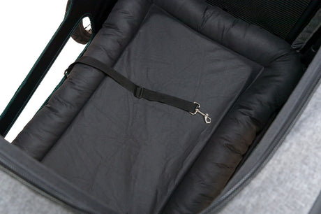 Innenansicht eines Fahrradanhängers mit schwarzer Polsterung und einem schwarzen Gurt mit silbernem Haken.