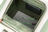 Geöffneter, grüner Rucksack mit grauem Fleeceboden und einem grünen Gurt mit Metallkarabiner innen.