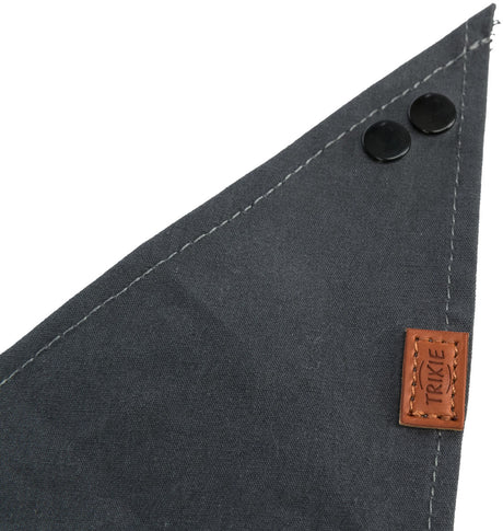 Dunkelgraues Stoffdreieck mit zwei schwarzen Knöpfen und einem braunen, eckigen Label mit der Aufschrift "TRIXIE".