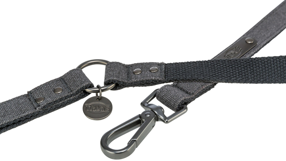 Graues Hundehalsband mit Metallring und Karabinerhaken, an dem ein rundes Trixie-Emblem hängt.