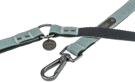 Grüne Hundeleine aus Stoff mit schwarzem Ring, Metallkarabiner und rundem Anhänger mit der Aufschrift "Trixie".