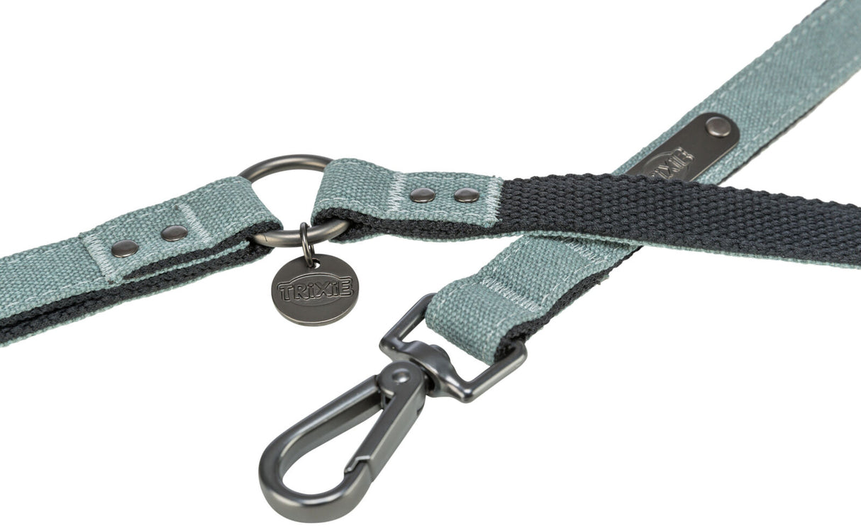 Grüne Hundeleine aus Stoff mit schwarzem Ring, Metallkarabiner und rundem Anhänger mit der Aufschrift "Trixie".
