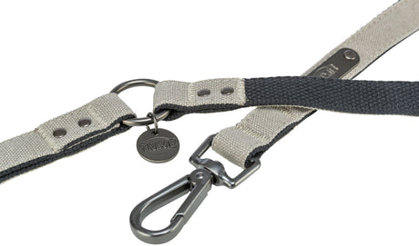 Grau-schwarze Hundeleine mit Karabinerhaken und Metallplakette, Markenname "Trixie" erkennbar.