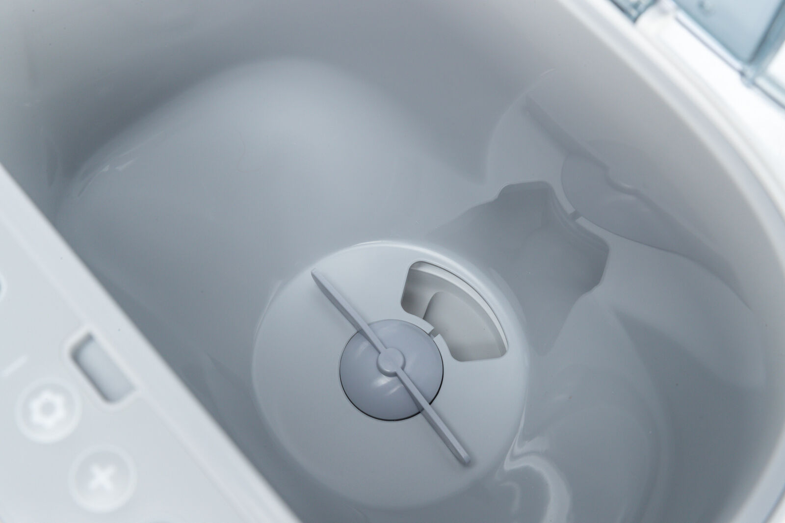 Weiße Innenansicht eines Kunststoffbehälters mit runder Vertiefung und zentralem Element, Licht reflektiert auf der Oberfläche.