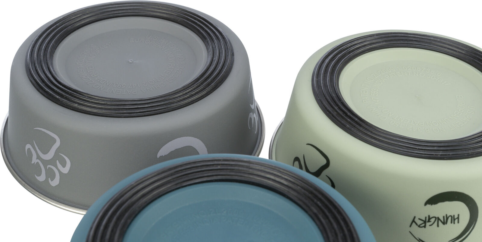 Drei umgedrehte Futternäpfe in Grau, Blau und Grün mit schwarzen rutschfesten Ringen und Aufschriften auf der Unterseite.