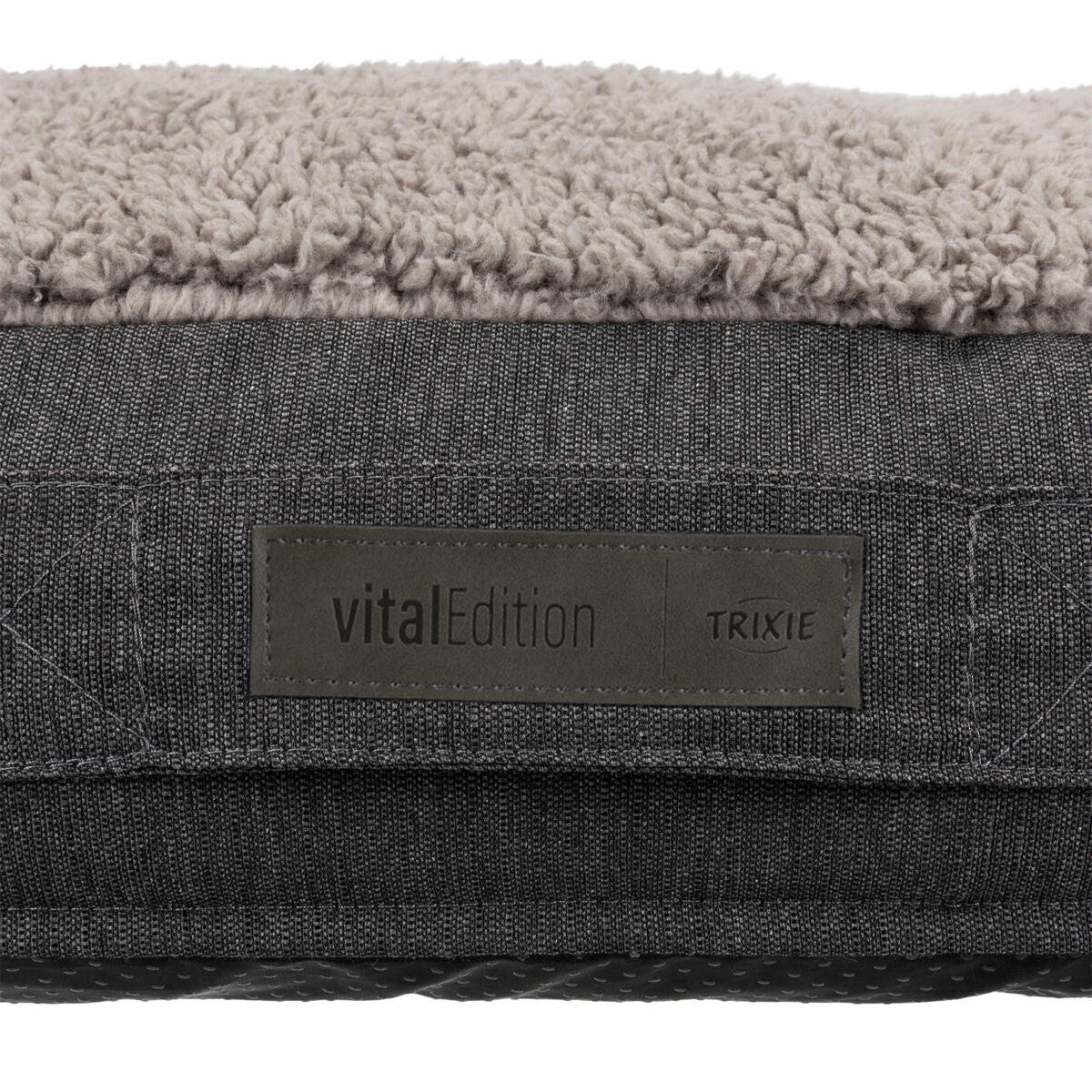 Graues, strukturiertes Material mit heller, plüschiger Oberseite und einem Etikett mit der Aufschrift "vitalEdition Trixie".