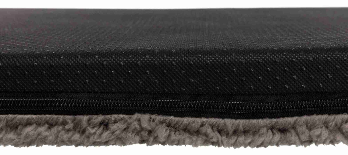 Schwarze, strukturierte Oberfläche über einem Reißverschluss mit darunter sichtbarem grauem, weichem Material.