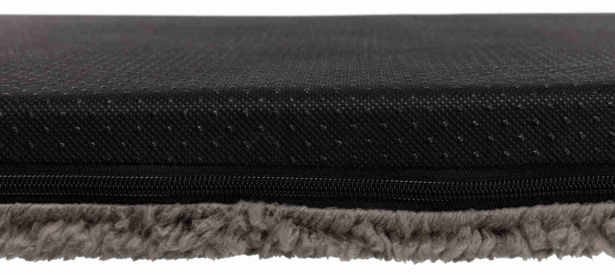 Schwarze, strukturierte Oberfläche über einem Reißverschluss mit darunter sichtbarem grauem, weichem Material.