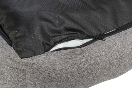 Nahaufnahme eines grauen Stoffpolsters mit einem geöffneten schwarzen Reißverschluss und schwarzem, perforiertem Innenfutter.