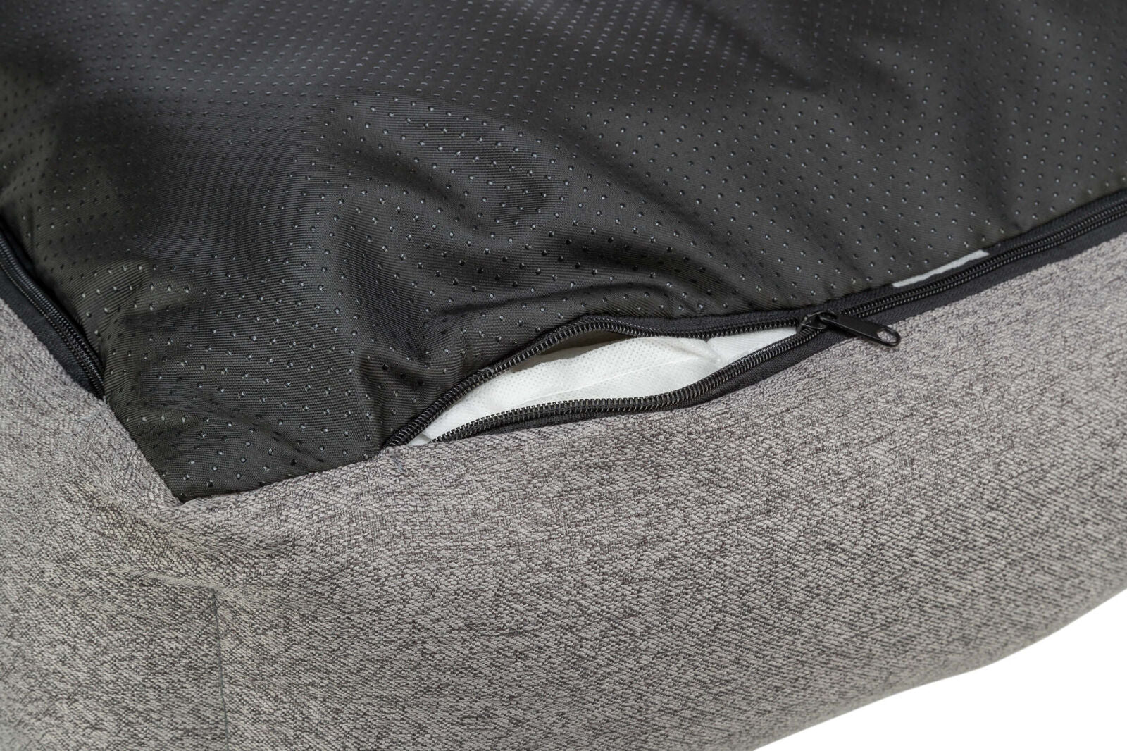 Nahaufnahme eines grauen Stoffpolsters mit einem geöffneten schwarzen Reißverschluss und schwarzem, perforiertem Innenfutter.