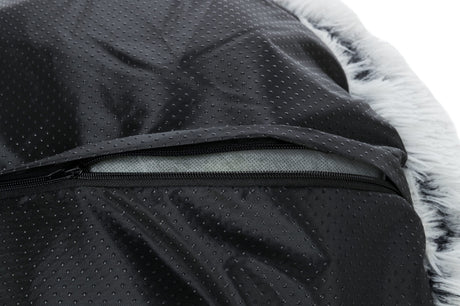 Nahaufnahme eines schwarzen, gepunkteten Stoffes mit einem halb geöffneten Reißverschluss und weißem, fellartigem Rand.