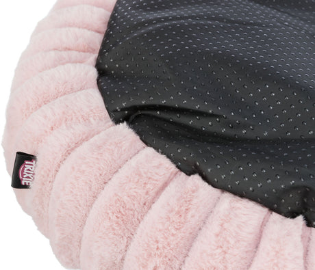 Teil eines runden, rosa Plüschkissens mit schwarzer, gepunkteter Oberfläche und sichtbarem Etikett.