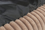Schwarzer, gepunkteter Stoff neben einem gestreiften, beige-braunem Pelzmaterial in Nahaufnahme.