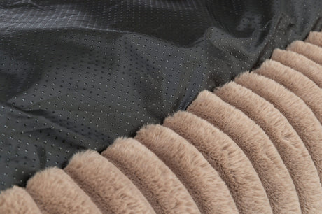 Schwarzer, gepunkteter Stoff neben einem gestreiften, beige-braunem Pelzmaterial in Nahaufnahme.