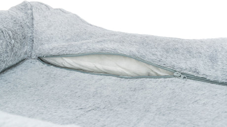 Graues, flauschiges Kissen mit einem Reißverschluss, der eine weiße, strukturiere Innenfläche zeigt.