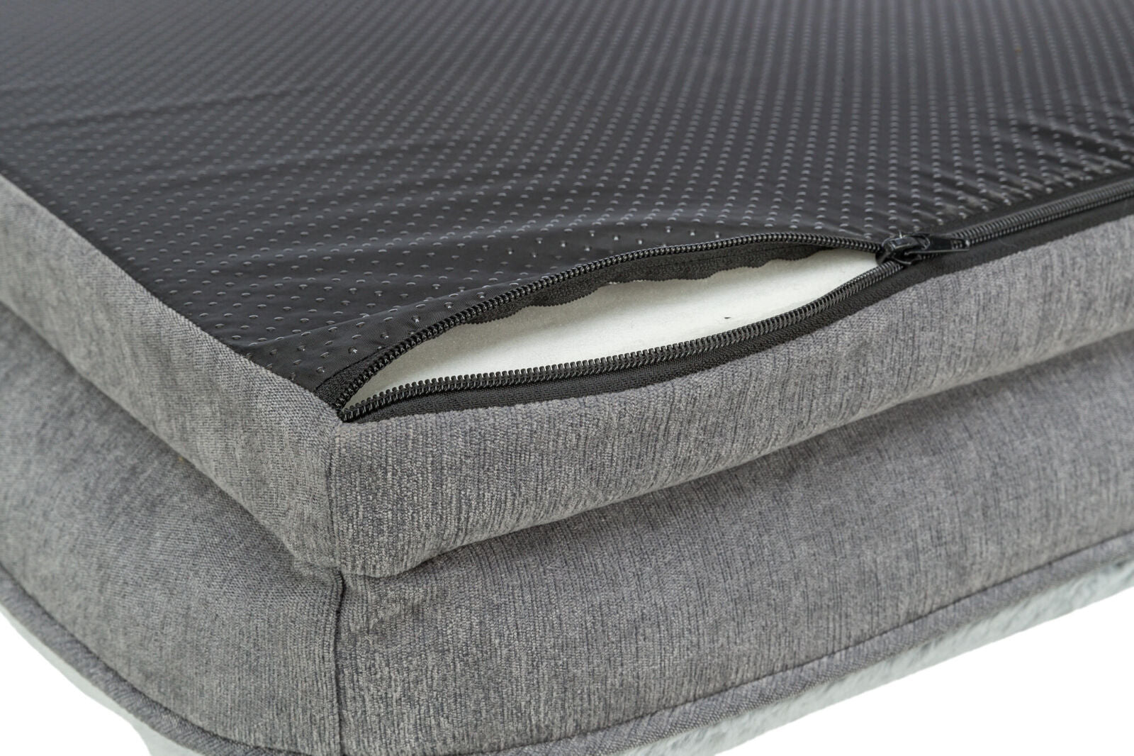 Graues Kissen mit schwarzem, perforiertem Bezug und offenem Reißverschluss, der weißen Innenstoff zeigt.