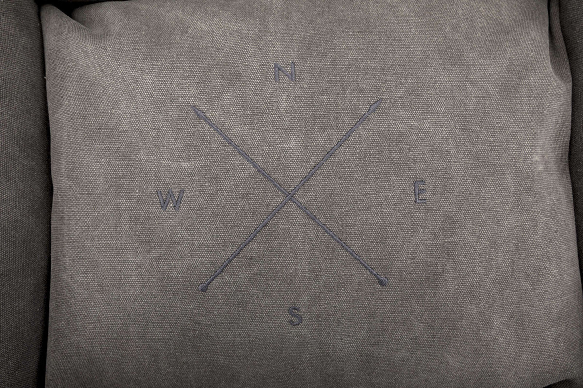 Graues quadratisches Muster mit vier Buchstaben N, E, S, W in den vier Ecken und zwei überkreuzten Linien.