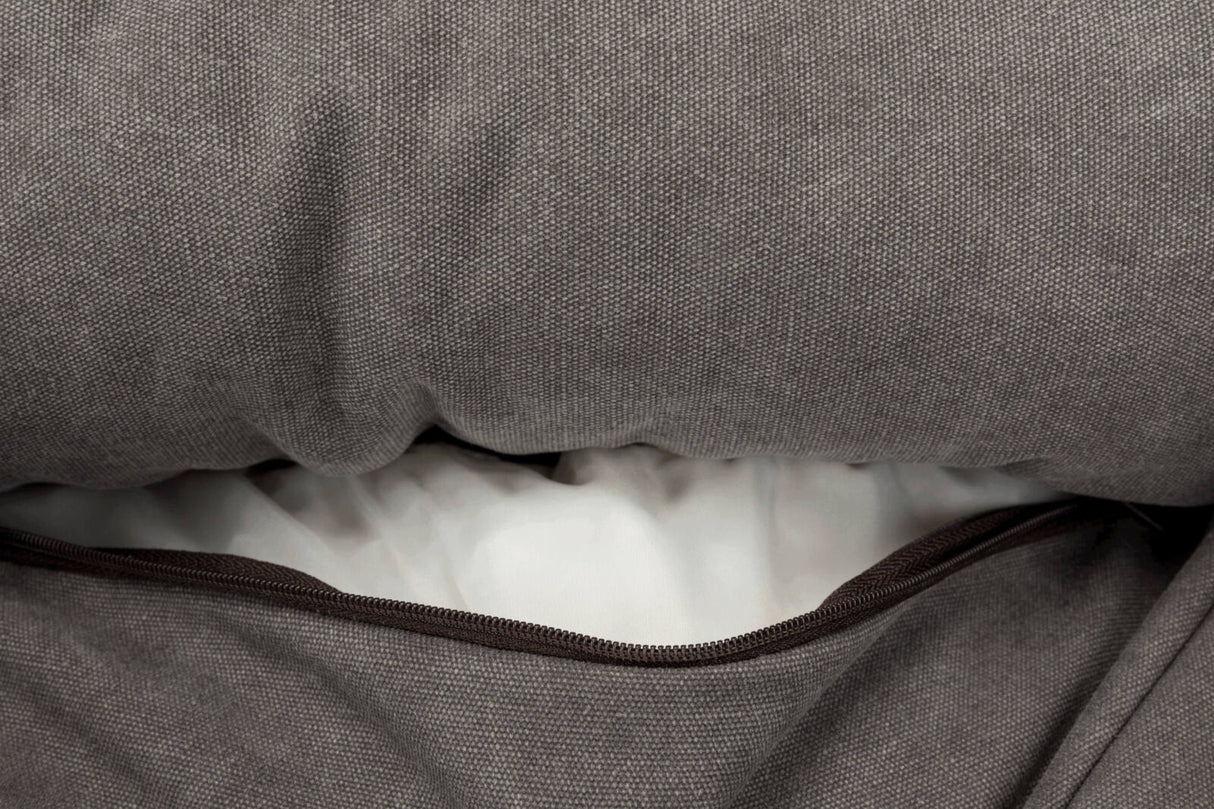 Grau melierter Stoff mit geöffneter Reißverschlussöffnung, die weißes Inneres eines Kissens zeigt.