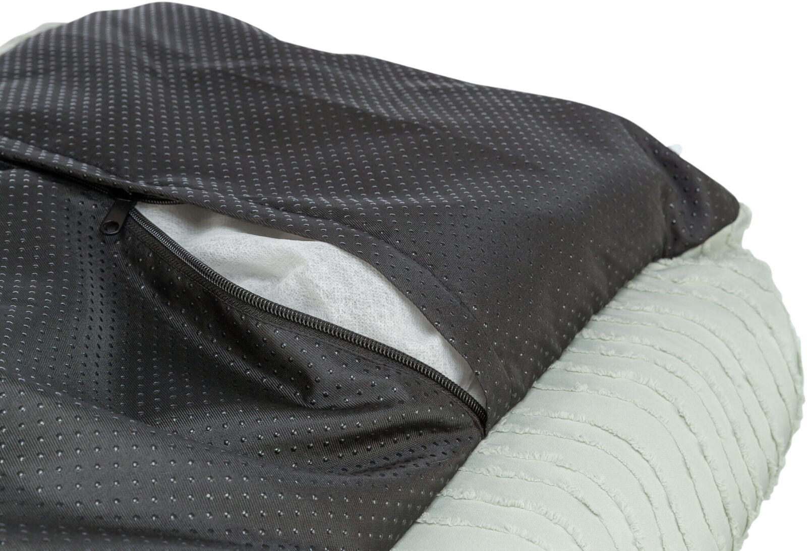 Schwarzes Textil mit Punktmuster und offenem Reißverschluss zeigt darunterliegendes weißes Gewebe.