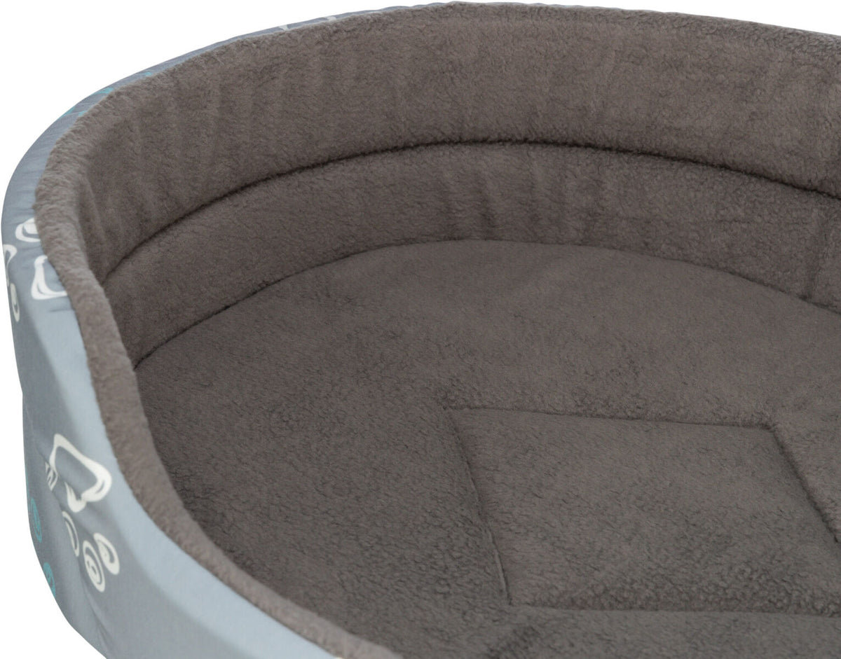 Graues, rundes Bett mit weicher, flauschiger Oberfläche und erhöhtem Rand, dekoriert mit weißen Mustern außen.