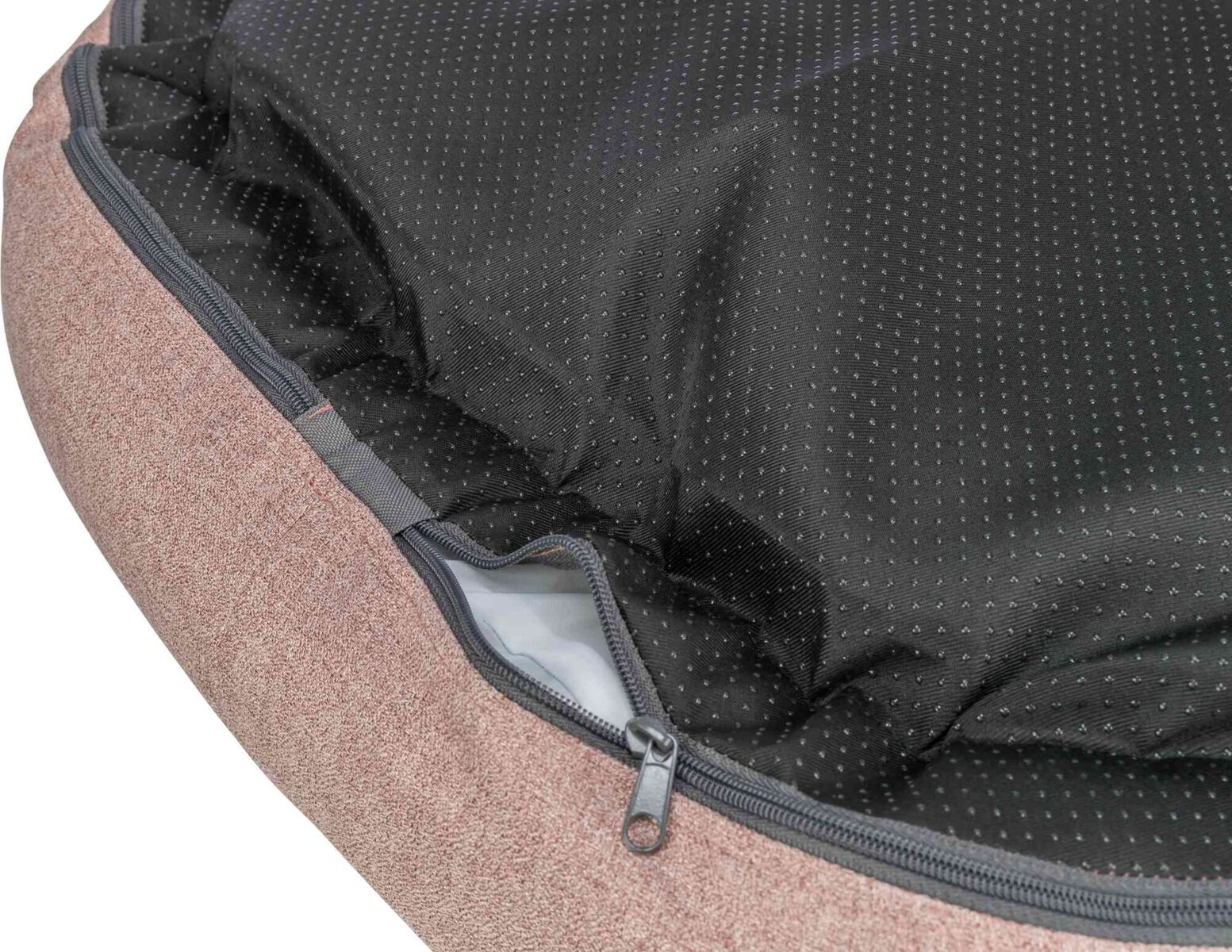 Nahaufnahme eines braunen Kissens mit strukturierter Oberfläche und schwarzem, gepunktetem Stoff mit Reißverschluss.