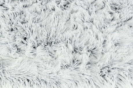 Flauschige, weiße Oberfläche mit dichtem, langem Flor aus weichem Material in unregelmäßigen Mustern.