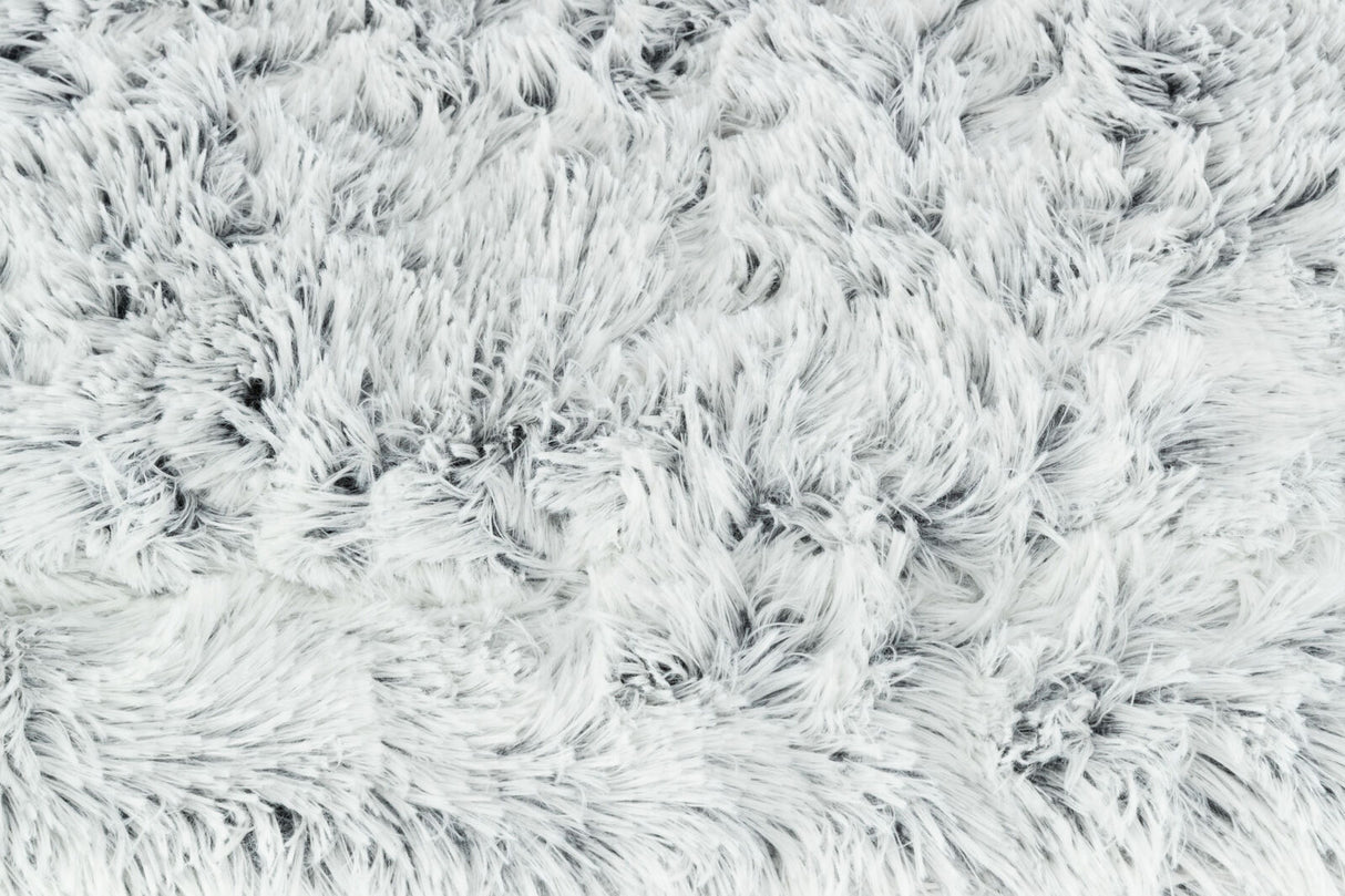 Flauschige, weiße Oberfläche mit dichtem, langem Flor aus weichem Material in unregelmäßigen Mustern.